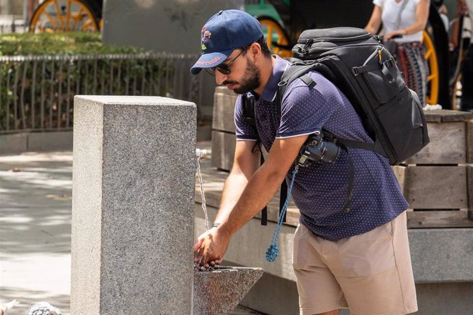 Archivo - Unos turistas junto a una fuente de agua pública,  en Sevilla. (Imagen de archivo).