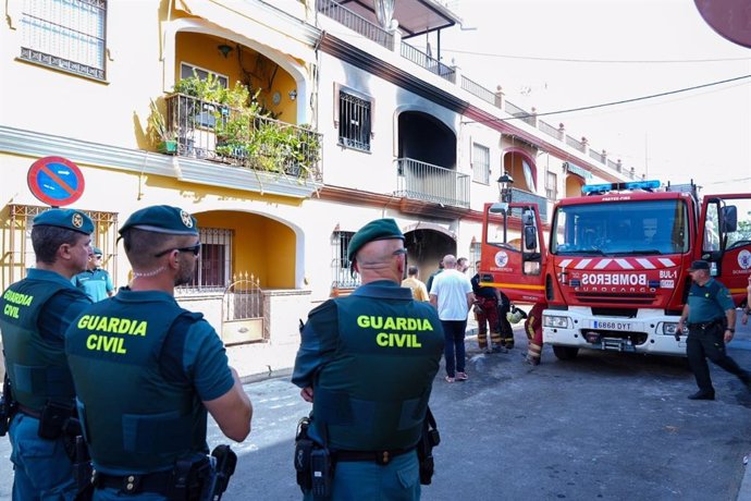 Agentes de la Guardia Civil y Bomberos en la calle frente a la casa incendiada.