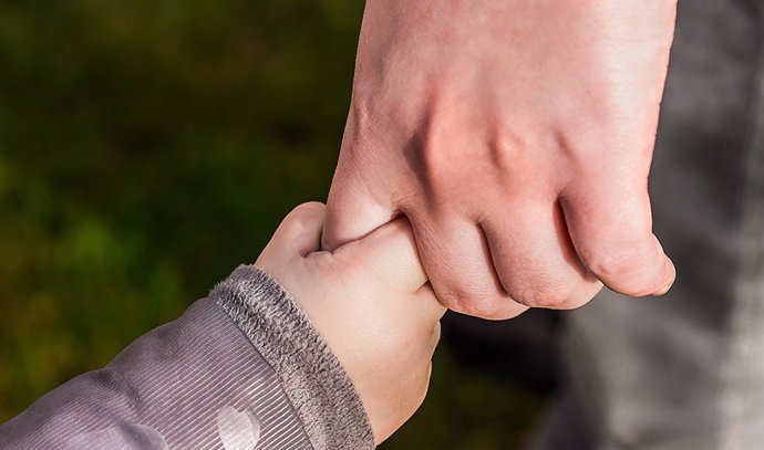 Imagen de recurso de un niño de la mano de un adulto