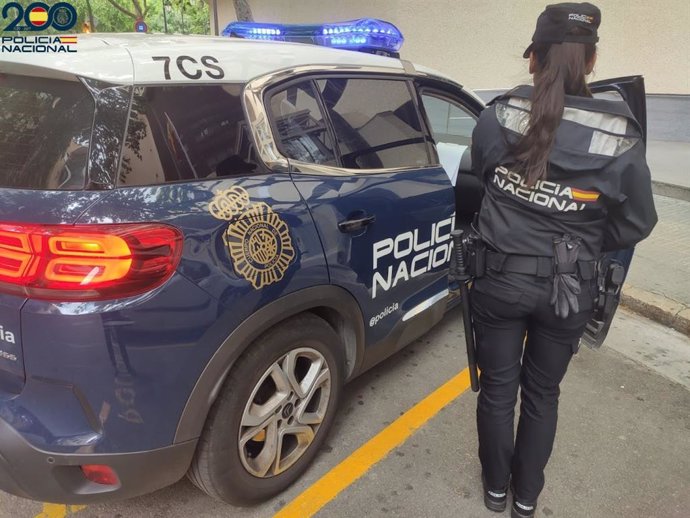 Unha axente da Policía Nacional xunto a un coche patrulla.