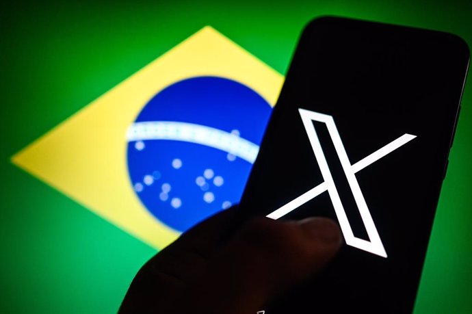 September 30, 2024, Poland: In this photo illustration an X logo (former twitter) logo is displayed on a smartphone with Brazil flag on the background.