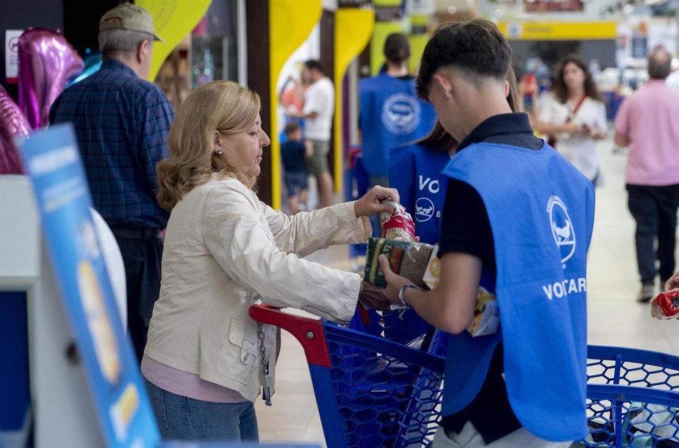 Archivo - Una mujer dona a un voluntario alimentos durante la Operación Kilo Primavera' organizada por la Federación Española de Banco de Alimentos (FESBAL).