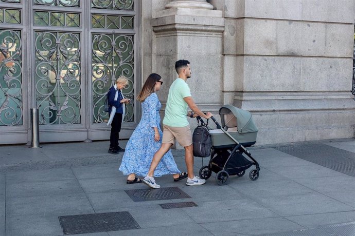 Una pareja pasea un carrito de bebé. 