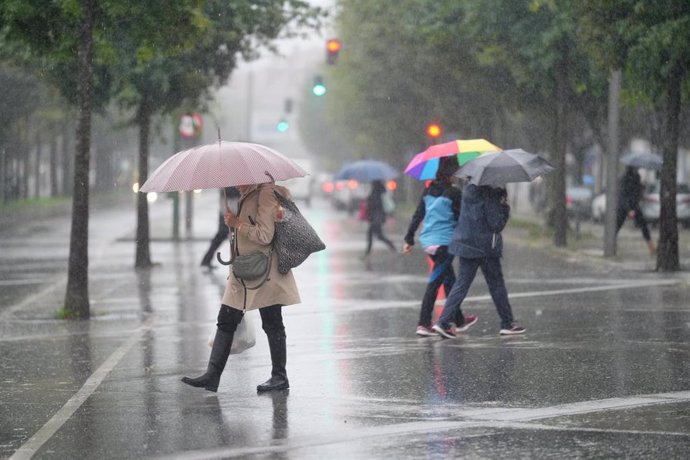 Varias personas caminan bajo la lluvia,