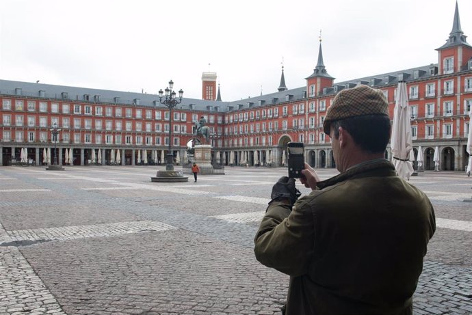 Archivo - Un hombre hace una foto con su móvil a la céntrica Plaza Mayor de Madrid, vacía durante el estado de alarma decretado por el coronavirus, en Madrid (España), a 16 de marzo de 2020.