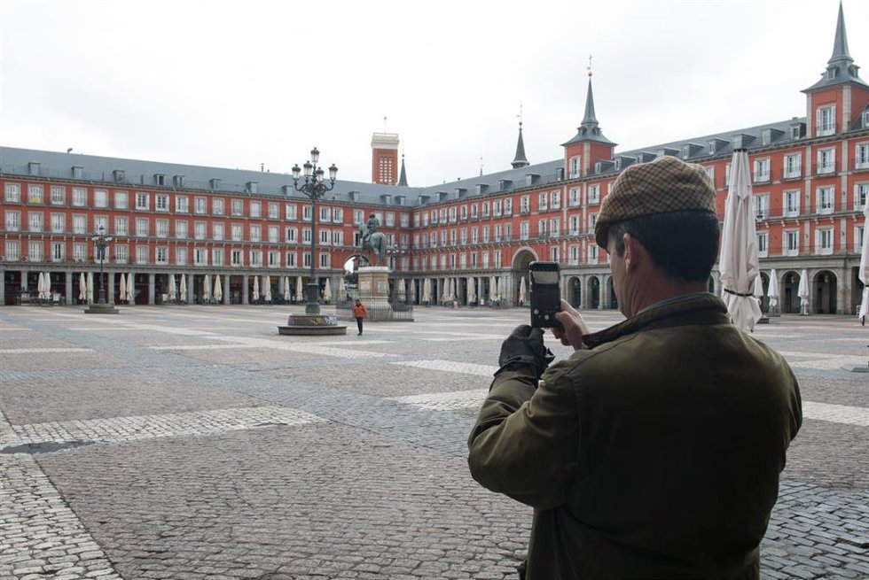 Archivo - Un hombre hace una foto con su móvil a la céntrica Plaza Mayor de Madrid, vacía durante el estado de alarma decretado por el coronavirus, en Madrid (España), a 16 de marzo de 2020.