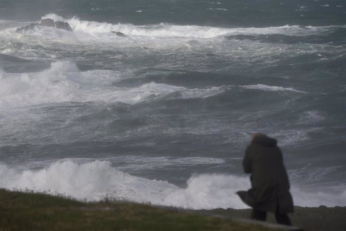 Archivo - Una persona se protege del oleaje en los alrededores de la Torre de Hércules, durante el paso de la borrasca ‘Ciarán’, a 3 de noviembre de 2023, en A Coruña, Galicia (España).  La borrasca 'Ciaran', que azota Galicia con fuertes vientos y lluvia