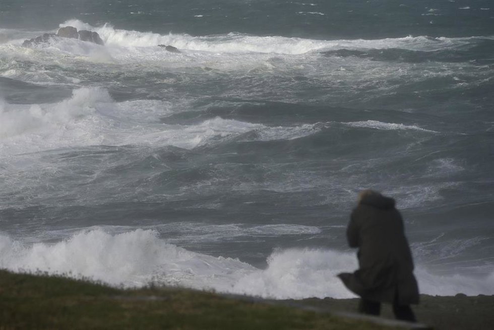 Archivo - Una persona se protege del oleaje en los alrededores de la Torre de Hércules, durante el paso de la borrasca Ciarán, a 3 de noviembre de 2023, en A Coruña, Galicia (España).  La borrasca 'Ciaran', que azota Galicia con fuertes vientos y lluv