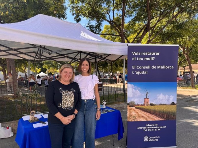 Antònia Roca, vicepresidenta del Consell de Mallorca (d), junto a un cartel de la campaña para subvencionar la reforma de molinos.