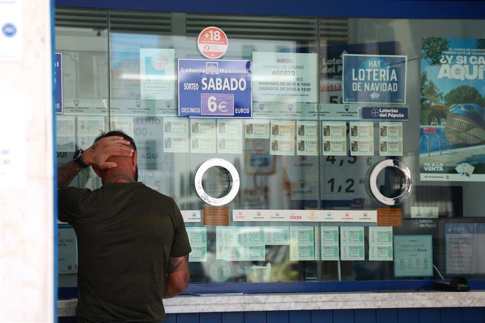 Archivo - Una persona se dispone a adquierir un boleto en una Administración de Loterias. Imagen de archivo.