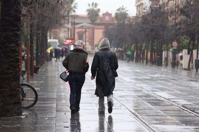 Archivo - Varias personas se protegen de la lluvia