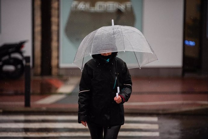 Archivo - Una persona se protege de la lluvia con paraguas.