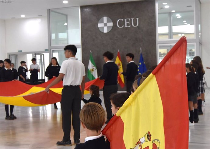 Alumnos del Colegio CEU San Pablo Sevilla participan en un acto homenaje a la bandera de España en el hall principal del centro.