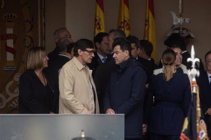 El presidente de la Generalitat de Catalunya, Salvador Illa (c), y el presidente de la Junta de Andalucía, Juanma Moreno (d), durante el acto solemne de homenaje a la Bandera Nacional y desfile militar por el 12 de octubre en Madrid.