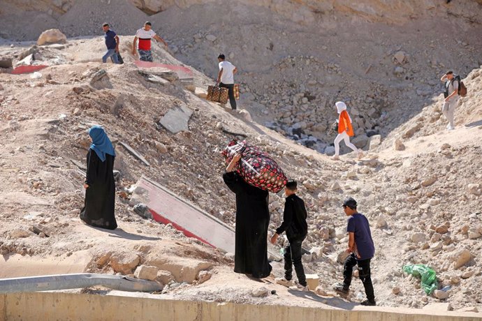 MASNAA BORDER CROSSING, Oct. 12, 2024  -- This photo shows displaced people from Lebanon crossing a hole on the road caused by an Israeli airstrike near the Masnaa Border Crossing, Lebanon, on Oct. 11, 2024. About a week ago, Israeli airstrike hit the Syr