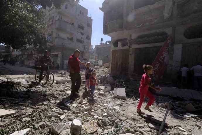 Palestinos frente a edificios destruidos por los ataques ejecutados por el Ejército de Israel contra el campamento de refugiados de Bureij, en el centro de la Franja de Gaza (archivo)