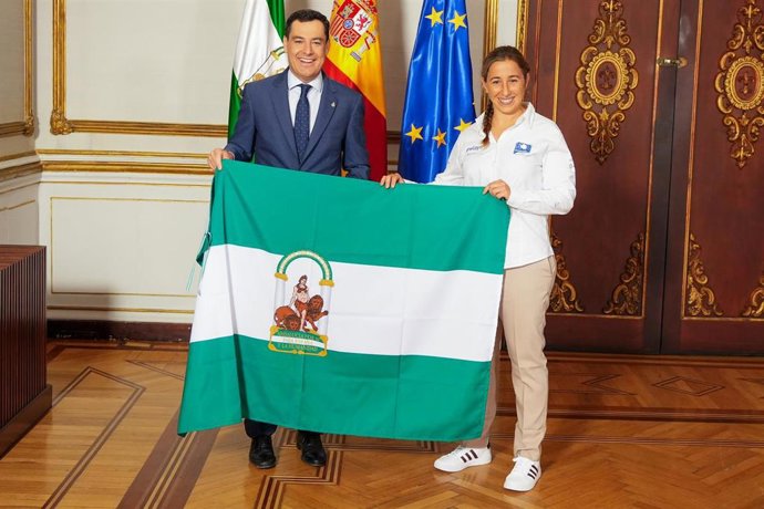 El presidente de la Junta de Andalucía, Juanma Moreno (i), entrega al bandea de Andalucía a la deportista Macarena Bohórquez (d), a 14 de octubre de 2024 en un acto celebrado en el Palacio de San Telmo.