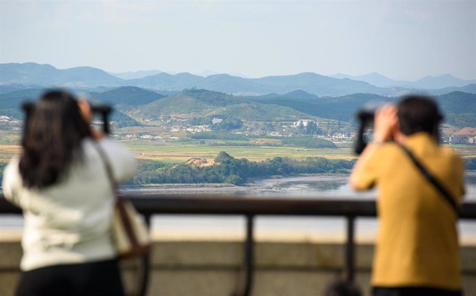 Un grupo de personas observa con prismáticos la frontera entre las dos Coreas