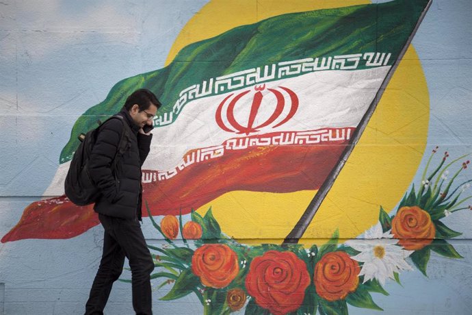 Archivo - February 17, 2020, Tehran, IRAN: Iranians walk next to a wall painting of the Iranian national flag in Tehran, Iran. Many Iranians, battered by economic sanctions, political turmoil and the lingering threat of military conflict, say they are in 