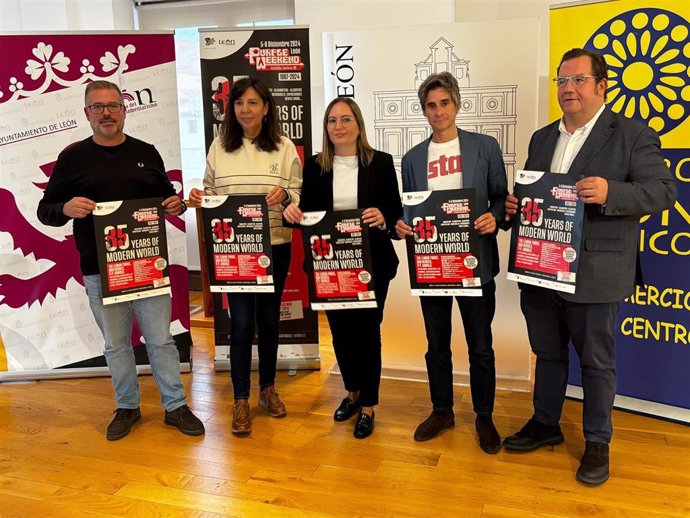 Organizadores del Purple Weekend de León posan junto a los carteles anunciadores del evento