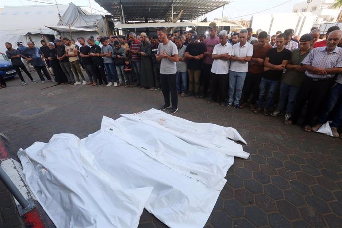 Un grupo de personas reza a sus muertos --víctimas de los ataques de Israel-- a las puertas de un hospital en Gaza.