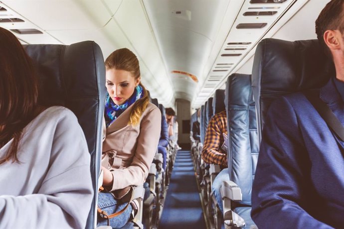 Archivo - Interior of airplane with people sitting on seats. Passengers on seat during flight.