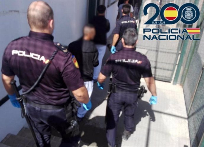 Agentes de Policía, junto al detenido tras la muerte de un hombre hallado en una patera con destino Almería junto a otros 16 inmigrantes