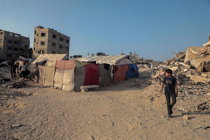 Un palestino pasea ante tiendas en un campamento de desplazados en Jan Yunis, en la Franja de Gaza