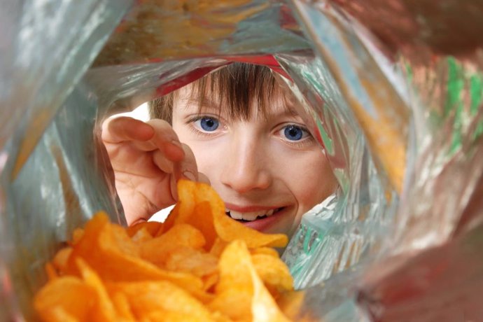 Archivo - Niño comiendo patatas fritas.