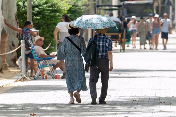 Archivo - Unos turistas pasean por la ciudad resguardados por un paraguas, a 19 de julio de 2024, en Sevilla, Andalucía (España). (Imagen de archivo).