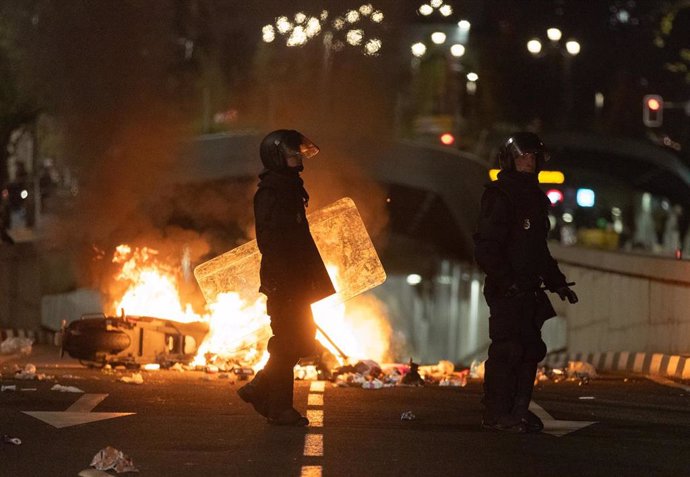 Archivo - Dos policías frente a una barricada de los manifestantes concentrados en la sede del PSOE en la calle Ferraz