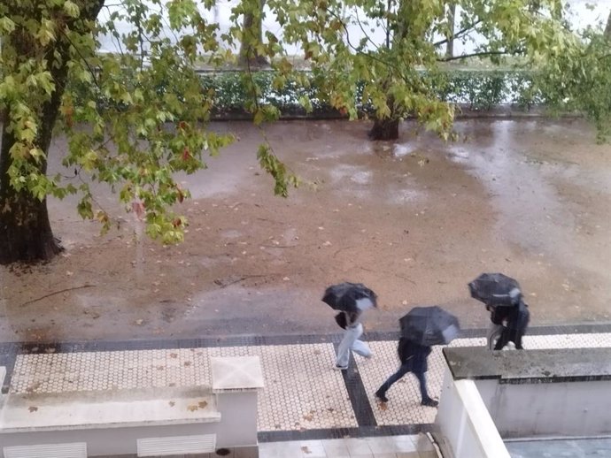 Varias personas pasean bajo la intensa lluvia en San Sebastián