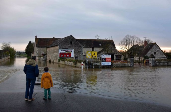 Archivo - 31 March 2024, France, La Roche-Posay: A man and a child stand in front of a flooded road near La Roche-Posay following heavy rains over the area. Photo: Pascal Lachenaud/AFP/dpa