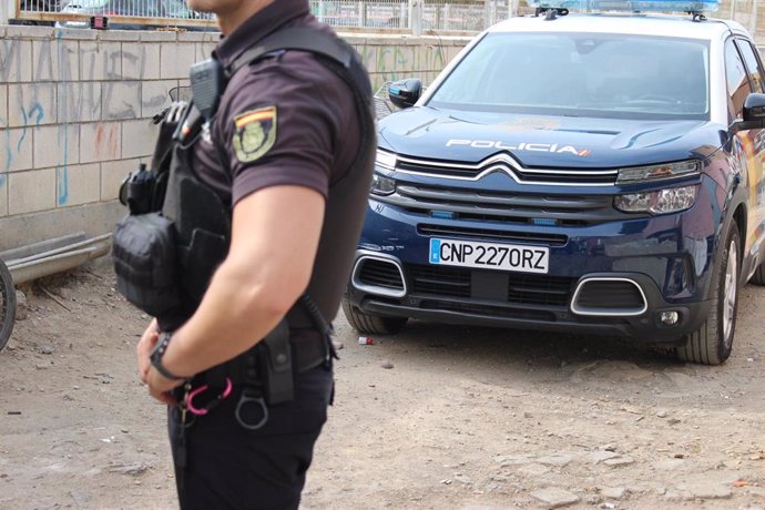 Archivo - Imagen de un agente y un coche patrulla de la Policía Nacional