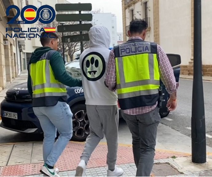 Agentes de la Policía Nacional custiodian a uno de los cuatro detenidos en Cádiz acusados de realizar estafas a través de internet.