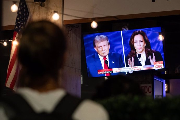  A person stops to watch a screen displaying the US Presidential debate between Vice President and Democratic presidential candidate Kamala Harris and former US president and Republican presidential candidate Donald Trump in Washington, DC