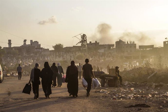 Un grupo de palestinos pasa por una calle bombardeada en la ciudad de Gaza