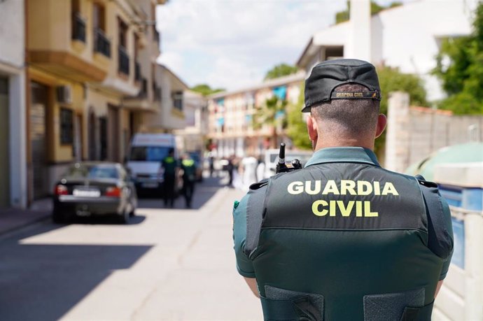 Archivo - Un agente de la Guardia Civil frente a unas viviendas en Granada