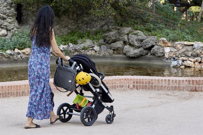 Archivo - Una mujer pasea con un carrito de bebé en el parque de El Retiro.