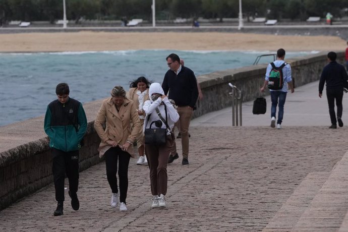 Archivo - Varias personas caminan bajo la lluvia en la playa de Ondarreta, a 14 de octubre de 2023, en San Sebastián, Guipúzcoa, País Vasco (España).