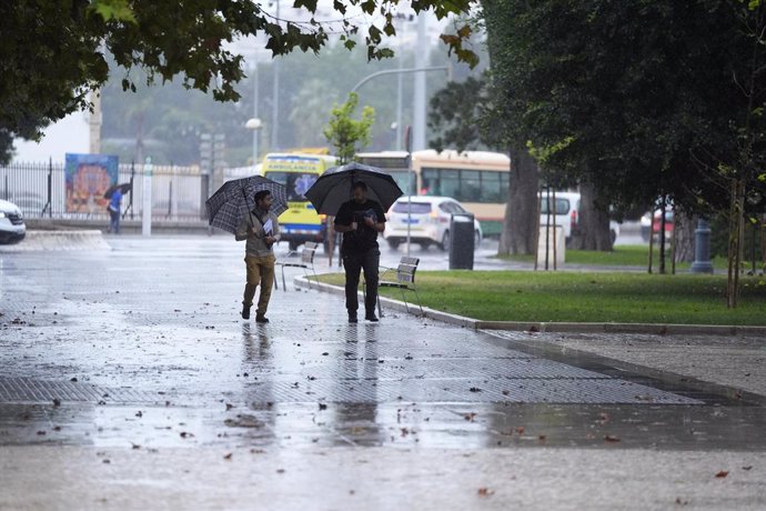 Transeuntes bajo sus paraguas durante la intensa lluvia. A 11 de octubre de 2024, en Cádiz (Andalucía, España). La Agencia Estatal de Meteorología (Aemet) ha activado para este viernes avisos de nivel naranja por lluvia y amarillo por tormenta en la mitad