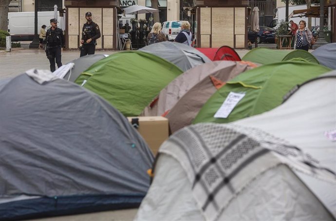 Dos agentes de Policía Nacional junto a las tiendas de campaña durante la acampada de vivienda en la Plaza del Ayuntamiento de València