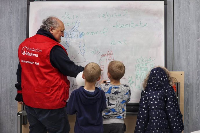 Archivo - Un voluntario de la Fundación Madrina dibuja con unos niños mientras sus madres recogen ropa de invierno q se entregan a familias en riesgo de vulnerabilidad en la sede de la Fundación Madrina, a 10 de febrero de 2023, en Madrid (España).