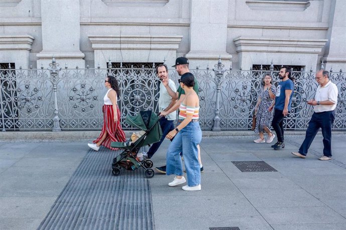 Varias personas pasean con un carrito de bebé 