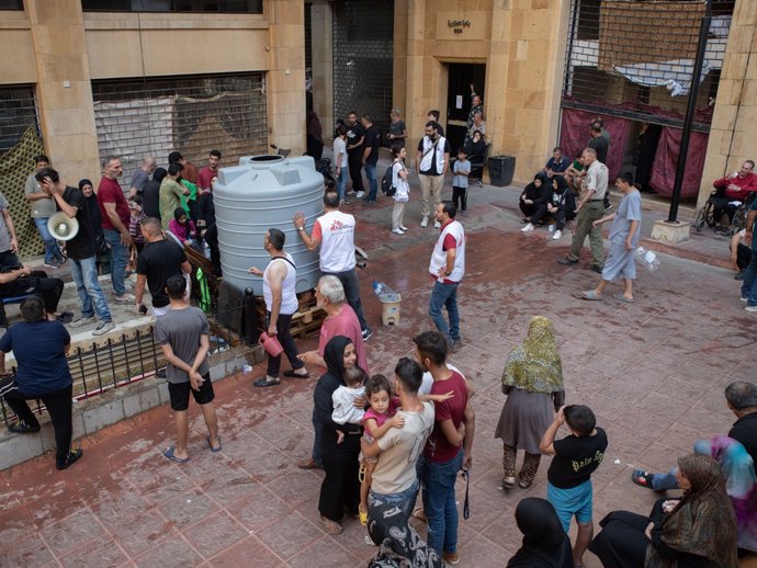 Familias desplazadas del refugio de Azarieh se agolpan en torno a un depósito de agua durante un reparto de agua en Beirut, Líbano.