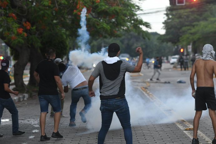 Archivo - 28 December 2022, Bolivia, Santa Cruz: Protesters throw gas grenades at police officers during a protest of supporters of opposition leader Camacho after his arrest. The opposition leader and governor of Santa Cruz was arrested for involvement i