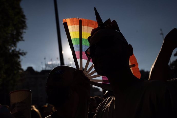 Archivo - Imagen de archivo de una persona con un abanico de la bandera LGTBI durante una manifestación 