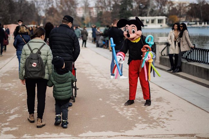 Archivo - Un niño observa a una persona disfrazada de Mickey en el parque del Retiro, a 25 de diciembre de 2022, en Madrid (España). 