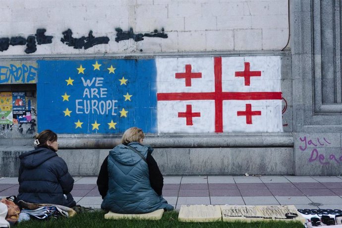 Georgianos en la capital del país, Tiflis, frente a un muro con pintadas de la bandera nacional y la de la Unión Europea