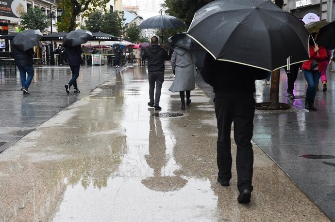 Archivo - Personas caminan por la calle con paraguas, a 13 de diciembre de 2022, en Madrid (España). La previsión de la Agencia Estatal de Meteorología (Aemet) en la Comunidad de Madrid para hoy apunta a que las lluvias persistirán y que las temperaturas 